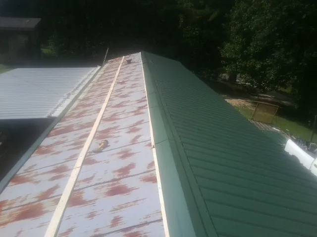 Old rusted panels beside newly installed green metal roofing — Wind Damage Roof Repair by Roofing Brothers in Suwanee