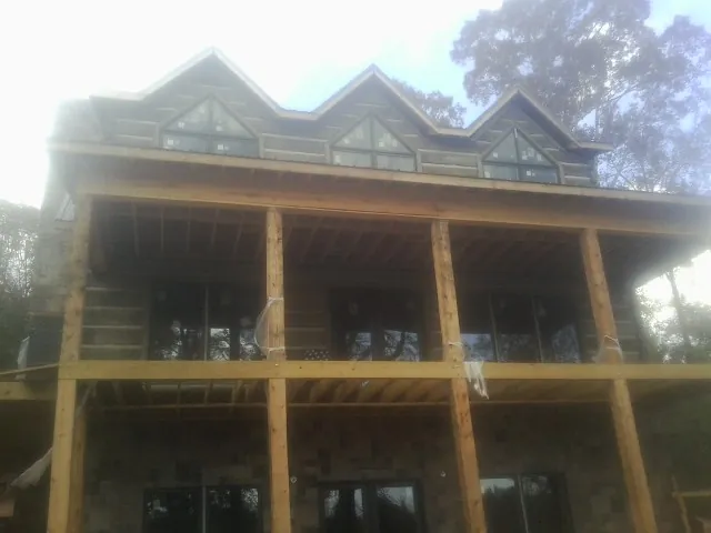 Dormers and porch framing on a large log home under construction — Roof Coating work by our crew in Suwanee