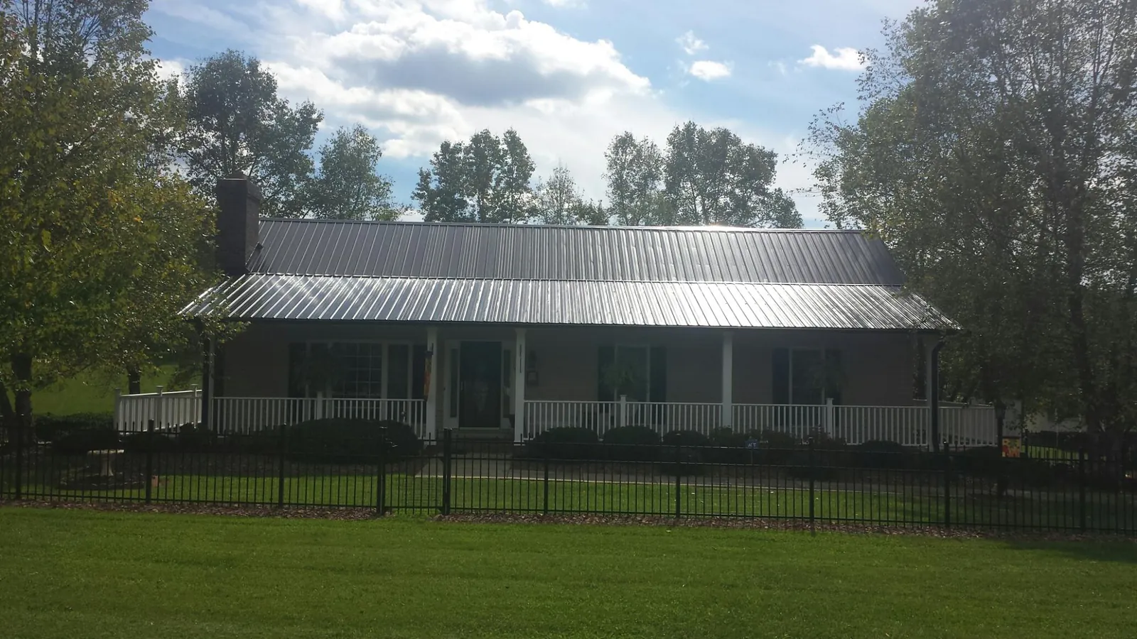 Gray metal roof on a brick ranch with a full width front porch — Gutter Guard Installation work by our crew in Suwanee