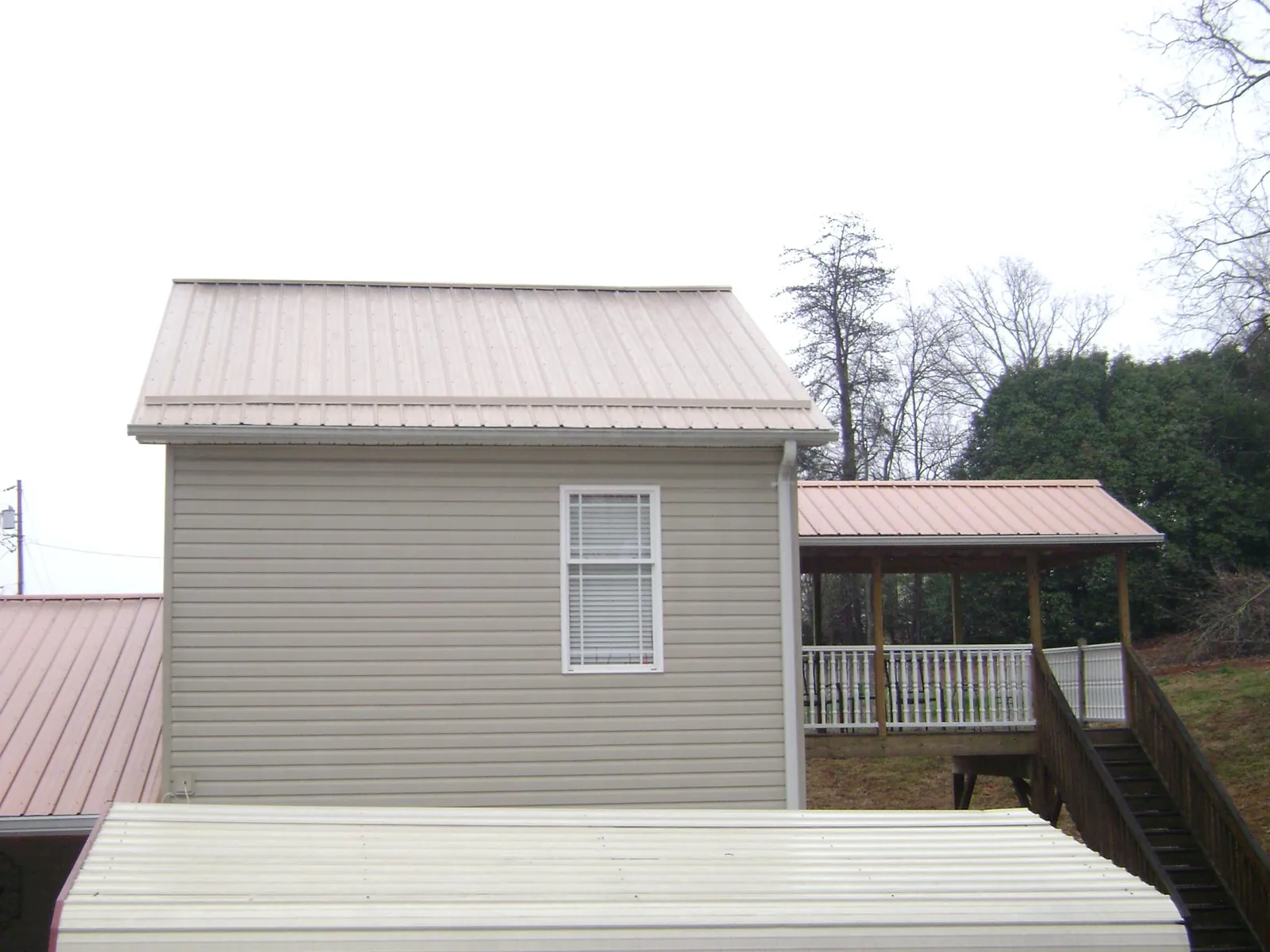 Tan metal roofs on a two story addition and attached porch, from a Roof Replacement job in Suwanee