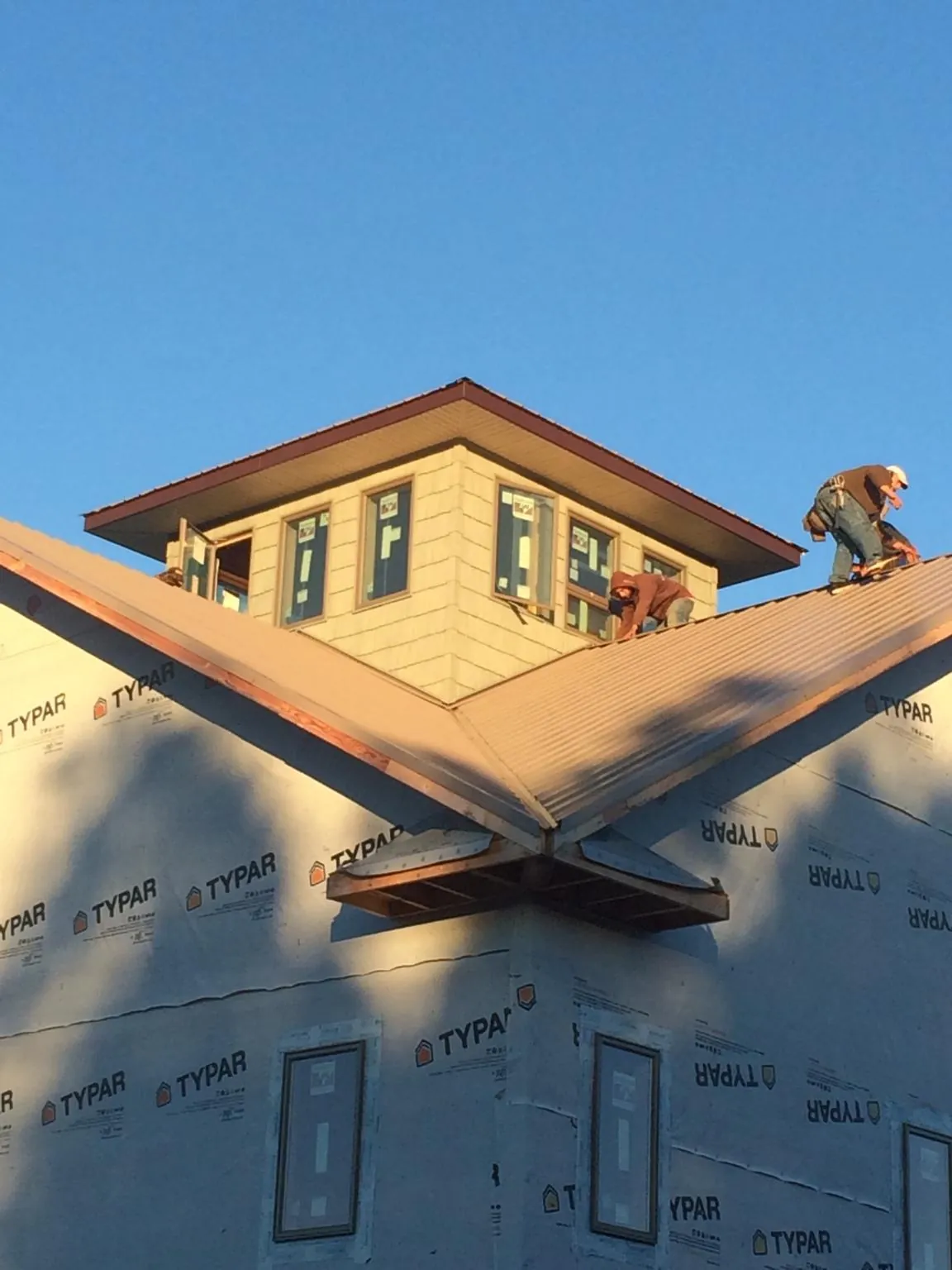 Roofers working around a rooftop cupola on a new metal roof at sunset — Roof Waterproofing in Suwanee by Roofing Brothers